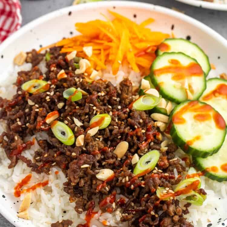 a korean rice bowl with ground beef and veggies.