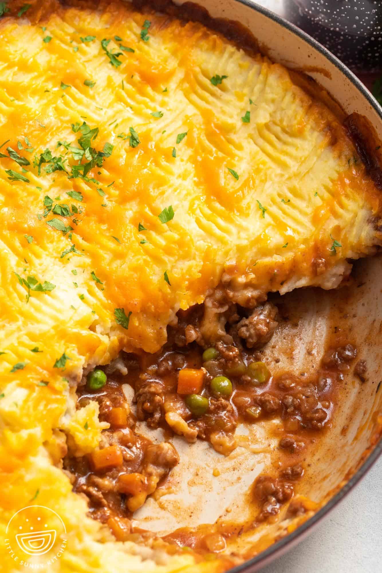 Cottage pie in a round baking dish. The pie has been served, showing the meat and vegetable filling inside.