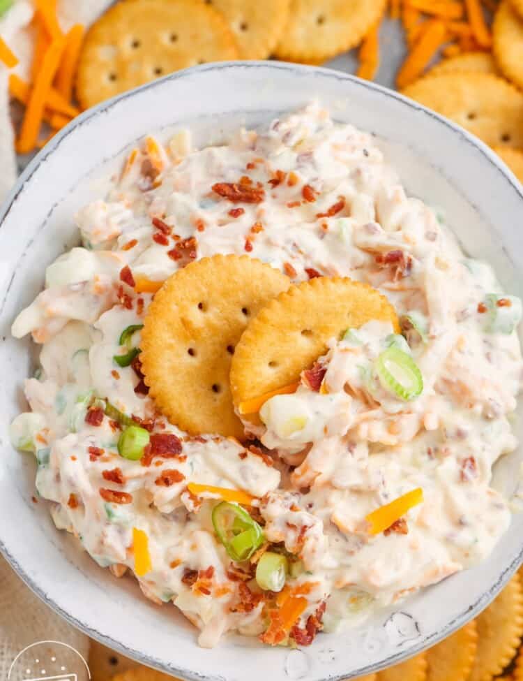 top down view of a bowl of million dollar dip on a platter of crackers.