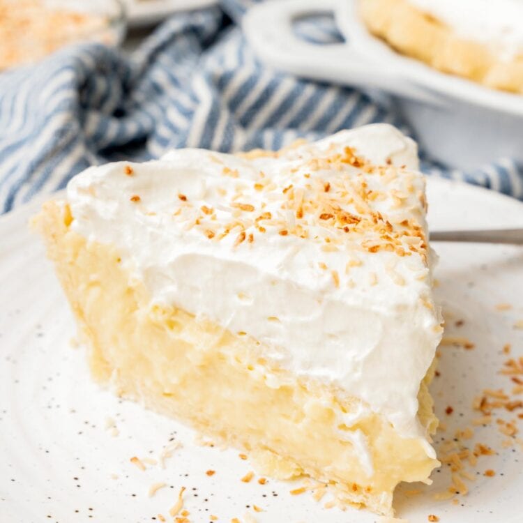 a generous slice of coconut cream pie on a white ceramic plate.