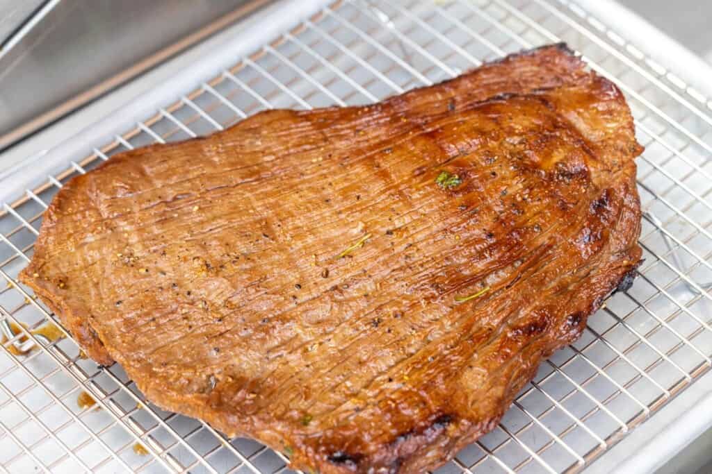 Cooked carne asada, resting on a wire rack.