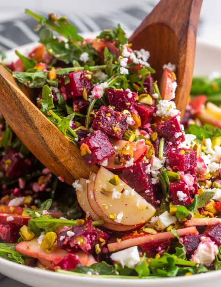 Tossing beet salad with feta cheese using 2 wooden servers